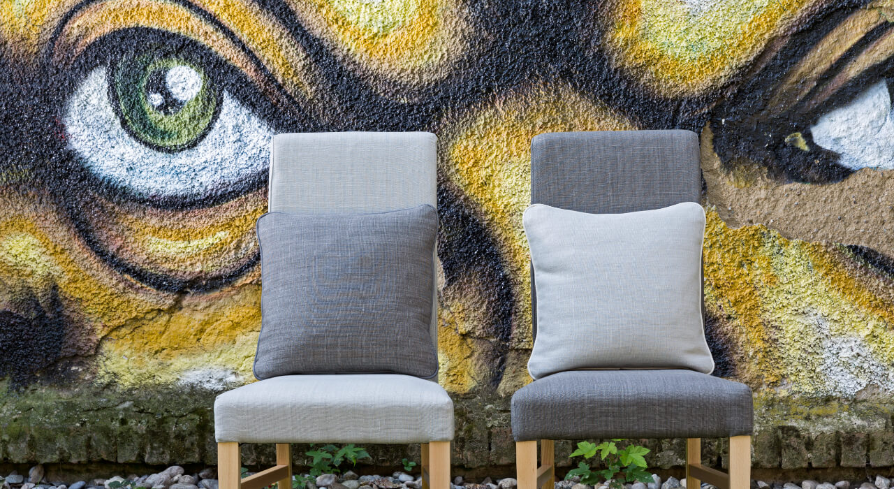 2 graue Stühle vor Grafity Wand